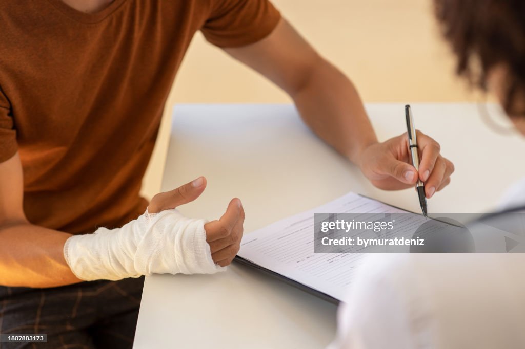 Man with broken arm filling health insurance claim form. Accident insurance disability compensation