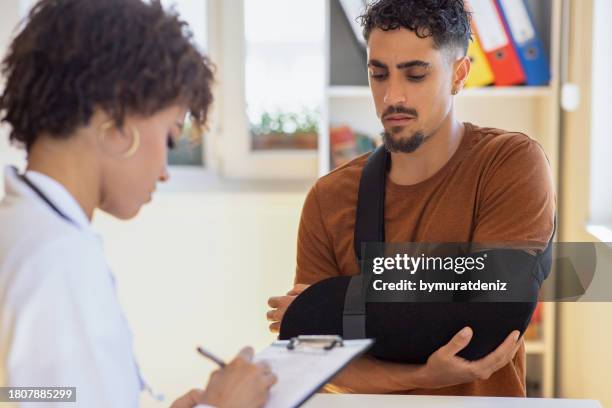 doctor at hospital prescribing treatment and talking to young patient - traumatology stock pictures, royalty-free photos & images