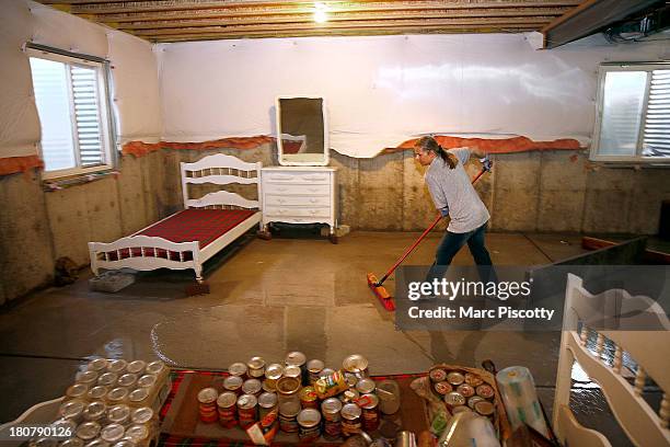 Jamie Bennett of Longmont, Colorado sweeps water towards a sump pump in a neighbor's basement as residents clean up in the wake of a week of heavy...