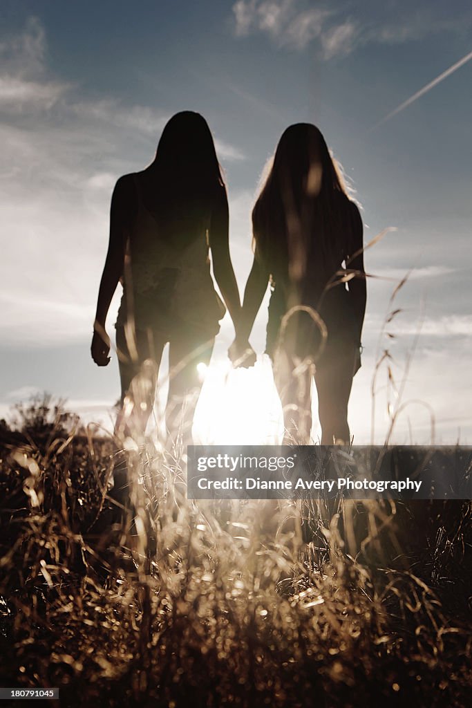 Silhouette of two teenage girls holding hands