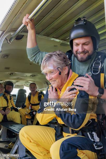 senior woman preparing for a tandem skydive with her instructor - komfortzone stock-fotos und bilder