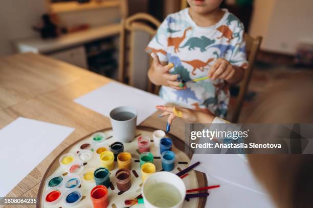 children dip their fingers in paint - 4 girl finger paint stock-fotos und bilder