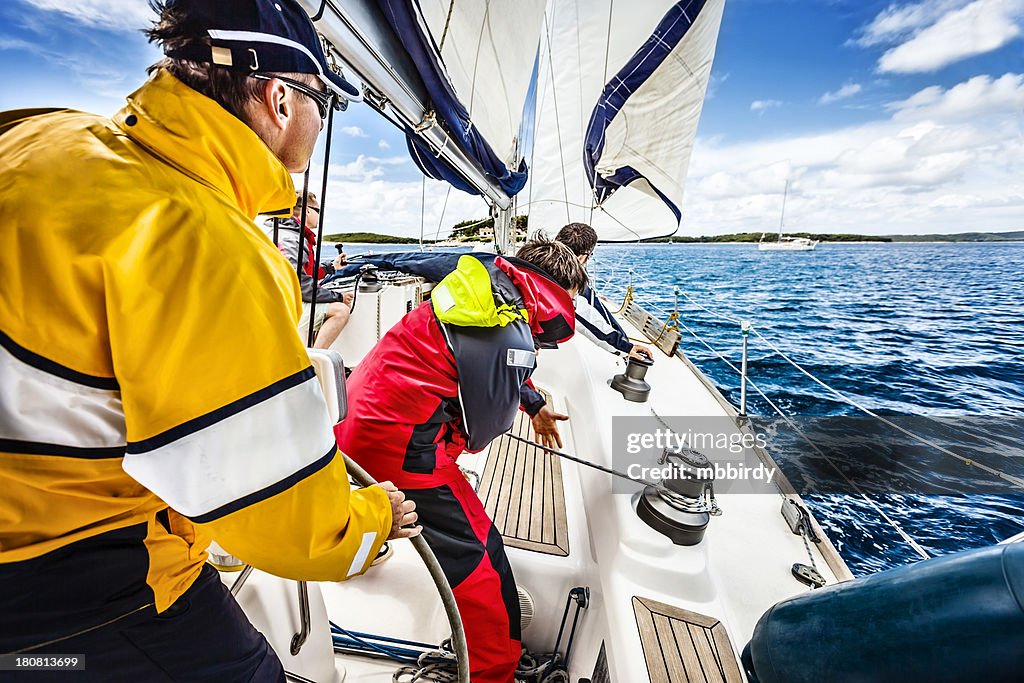 Sailing crew beating to windward on sailboat