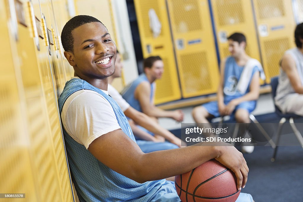 Happy teenage basketball player in high school locker room