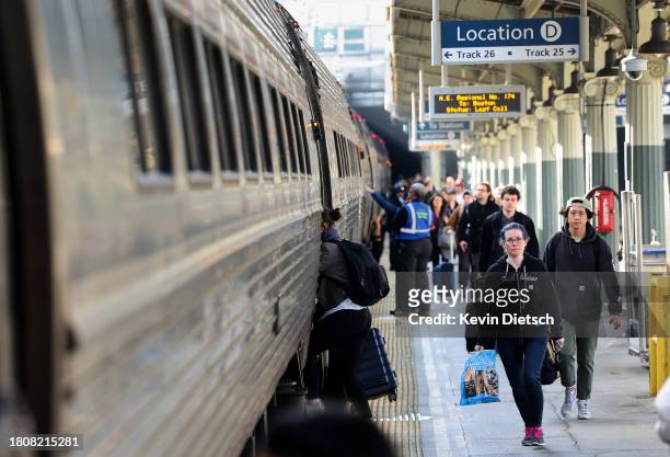 Travelers board an Amtrak train at Union Station on November 22, 2023 in Washington, DC. Flights, highways, trains, and other forms of transportation...
