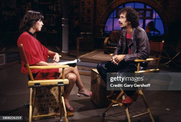 View of American MTV VJ Martha Quinn and Blues & Rock musician Carlos Santana, both sitting in director's chairs, during an interview on MTV at...
