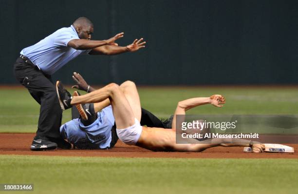 Fan of the Tampa Bay Rays attempts to steal second base and is tackled by a security guards in the 5th inning during play against the Texas Rangers...