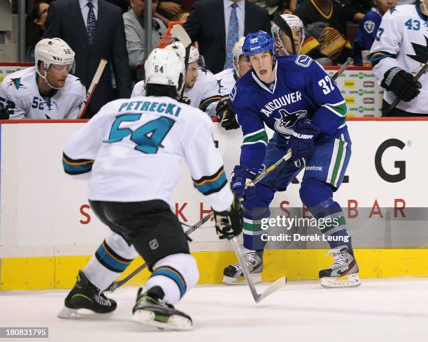 Dale Weise of the Vancouver Canucks looks to carry the puck past the defence of Nick Petrecki of the San Jose Sharks during a preseason NHL game at...