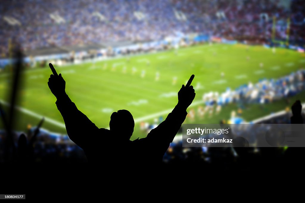 Silhouette of excited fans at football game