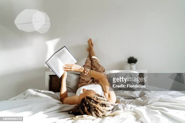 portrait of a woman with book lying on the bed - varices fotografías e imágenes de stock