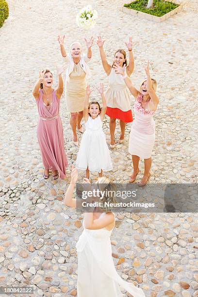 young bride throwing bouquet of flowers at guests - bouquet toss stock pictures, royalty-free photos & images