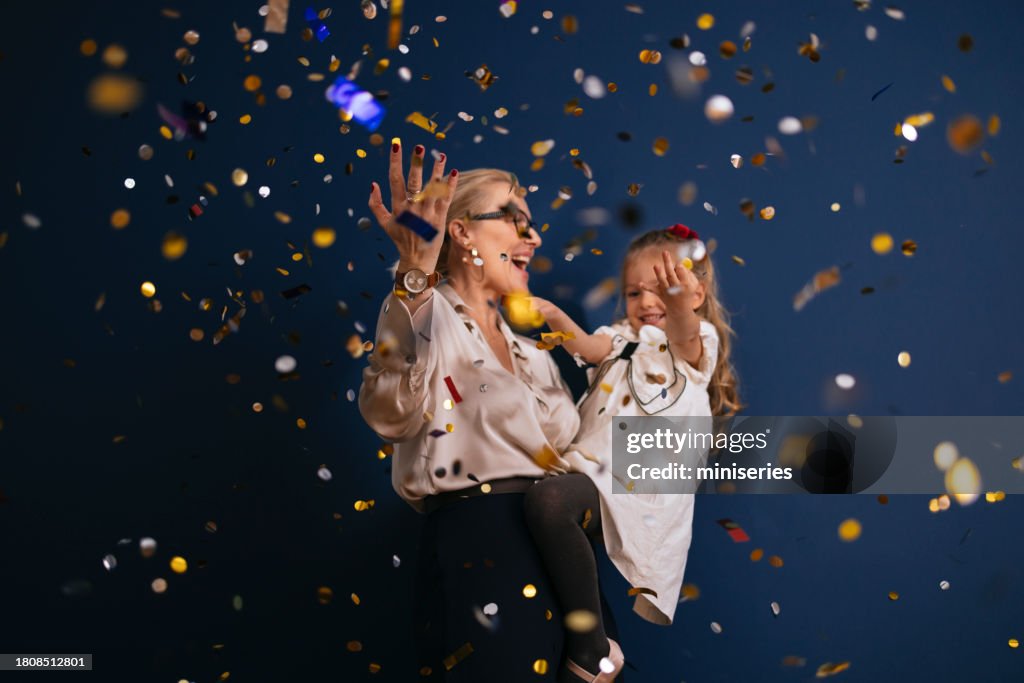 Portrait Of A Happy Mother And Daughter Dancing Together In Confetti Rain At Christmas Party
