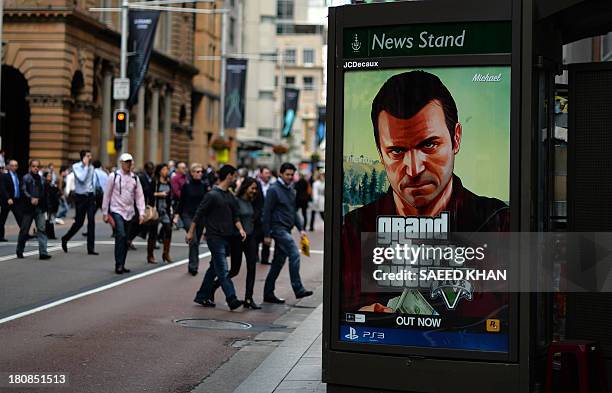 Commuters cross a main road next to an advertisement of console game Grand Theft Auto 5 in the central business district of Sydney on September 17,...