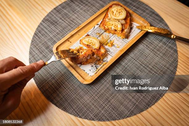 close up of the hands of a diner tasting a toast with goat's cheese and honey. - tellerlift stock-fotos und bilder