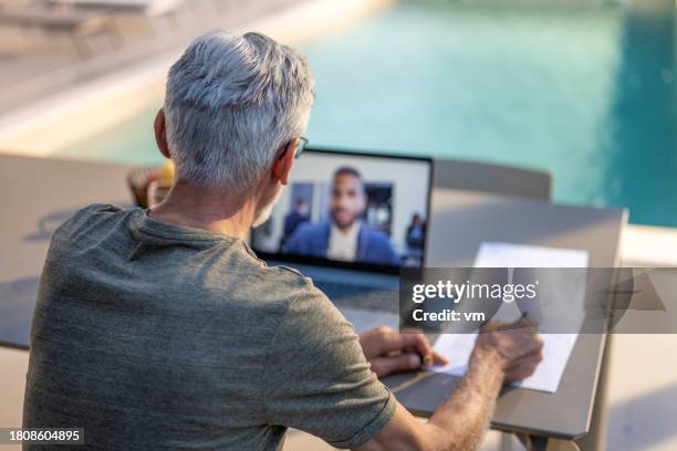 älterer mann spricht in videoanruf und macht sich notizen - old monitor computer stock-fotos und bilder