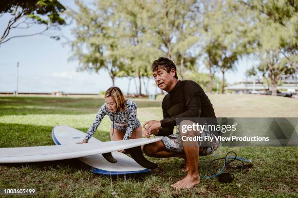 aktiver älterer mann bereitet sich darauf vor, mit seiner schwester surfen zu gehen - hawaiianischer-abstammung stock-fotos und bilder