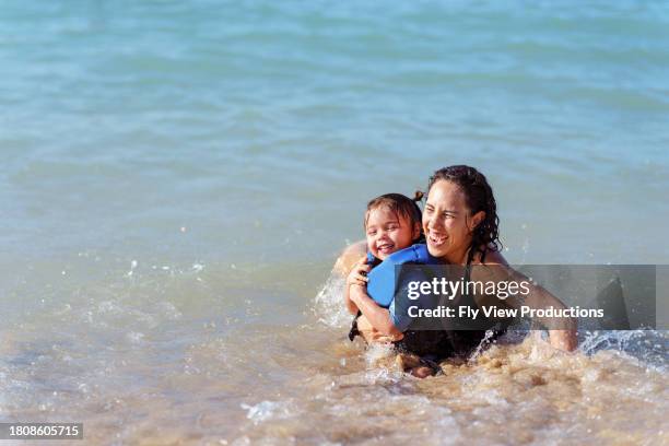 mãe e filha euroasiáticas rindo enquanto nadam no oceano - jaqueta salva vidas - fotografias e filmes do acervo