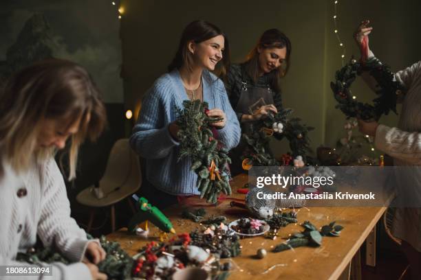 womans with florist making christmas wreath on master class. - decorating the christmas tree stock pictures, royalty-free photos & images
