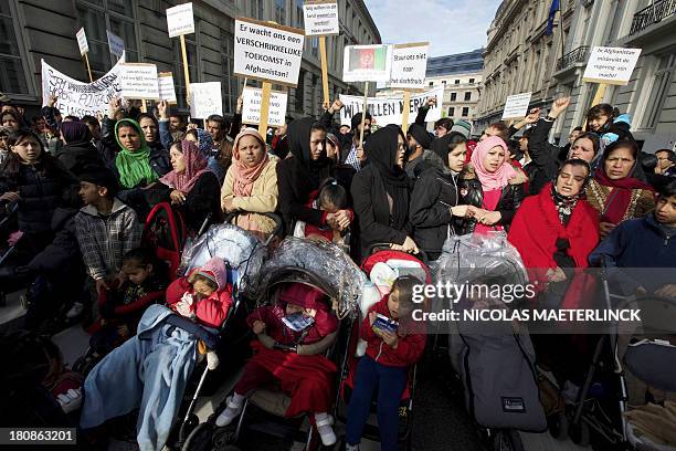 Afghan refugees hold signs as they demonstrate against Belgian State Secretary of Home Affairs Maggie De Block's policy near the Wetstraat street, in...