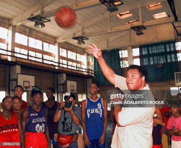 Boxing legend Muhammad Ali shoots a basketball towards the basket under the watchful eyes of members of the Cuban women's basketball selection at the...