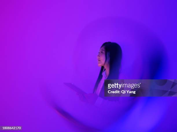 young asian woman using a digital tablet on neon color background - privacy policy stockfoto's en -beelden