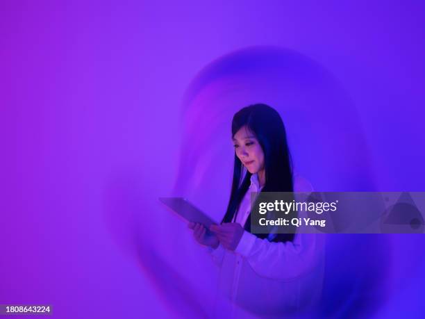 young asian woman using a digital tablet on neon color background - surrounding ストックフォトと画像