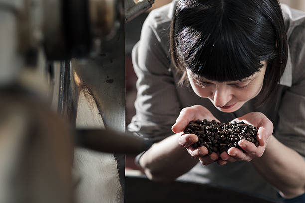 female small business owner smelling fresh roasted coffee - professional coffee roaster stock pictures, royalty-free photos & images