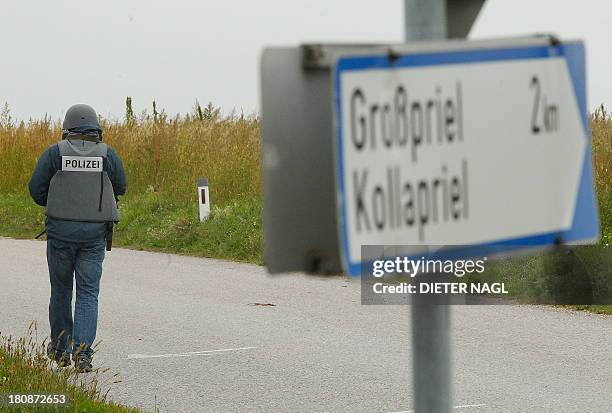 An Austrian police officier walks on a blocked road on September 17, 2013 near Grosspriel where a poacher has shut himself in a farmhouse with a...