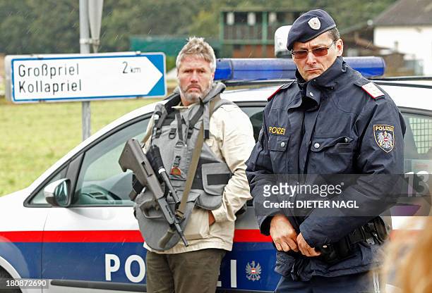 Austrian police officiers block a road on September 17, 2013 near Grosspriel where a poacher has shut himself in a farmhouse with a hostage. Police...