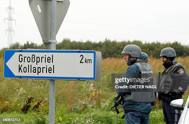 Austrian police officiers block a road on September 17, 2013 near Grosspriel where a poacher has shut himself in a farmhouse with a hostage. Police...