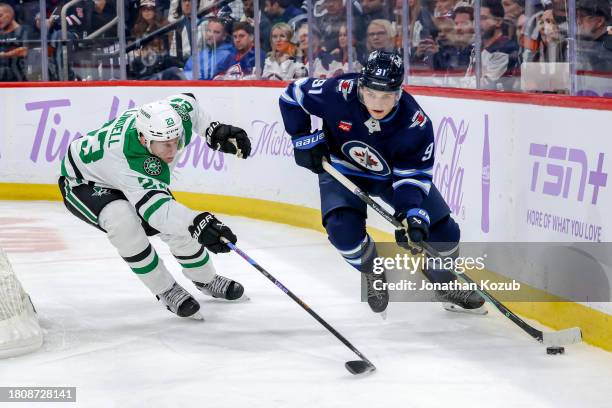 Cole Perfetti of the Winnipeg Jets plays the puck along the boards as Esa Lindell of the Dallas Stars defends during second period action at the...