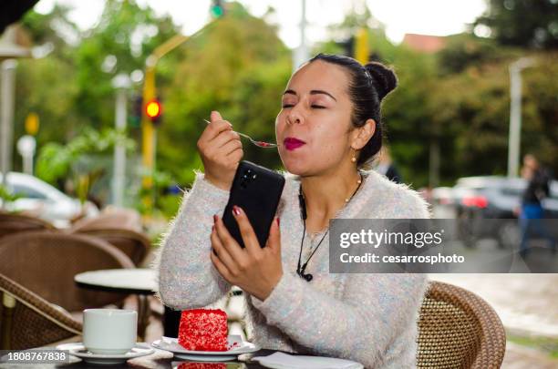 portrait of woman in coffee shop eating slice of cake and using smartphone - colombia business breakfast meeting stock pictures, royalty-free photos & images