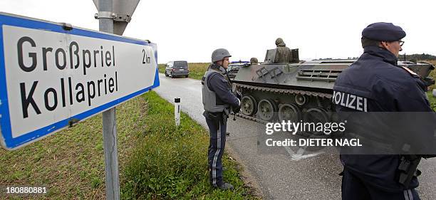 Policemen stand next to an armored vehicle of the Austrian army on September 17, 2013 on a road leading to Grosspriel, Austria, where a poacher has...