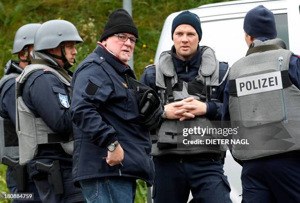 Armed police officers block a road near Grosspriel, some 65 kilometers west of Vienna, on September 17, 2013 where a man hides himself with a police...