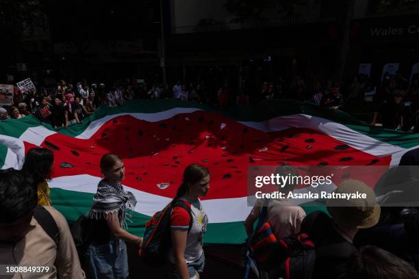 Protesters march holding a large flag in the shape of a watermelon on November 23, 2023 in Melbourne, Australia. Organised by School Students For...