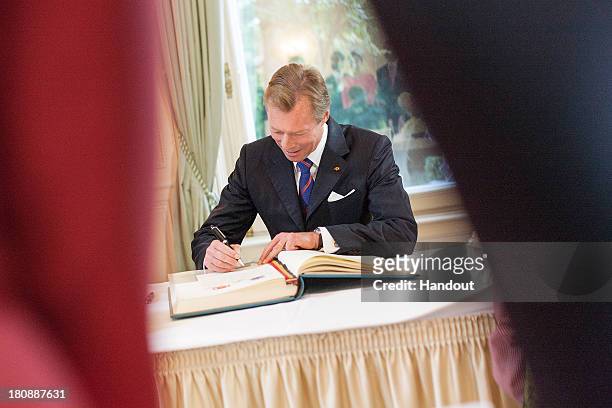 In this handout image provided by the Grand-Ducal Court of Luxembourg, His Royal Highness Grand Duke Henri of Luxembourg signs a document as he...