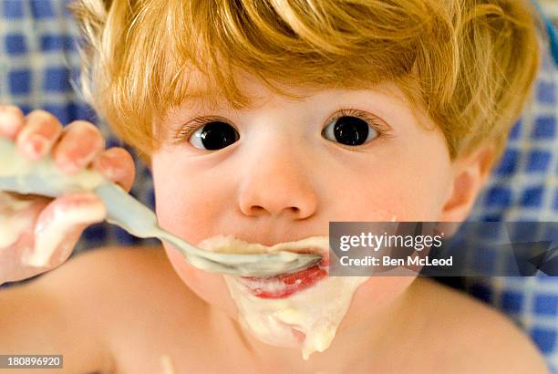 yogurt face - baby eating yogurt stockfoto's en -beelden