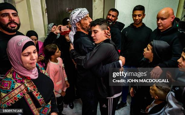 Ahmad Salaima, a 14-year-old Palestinian released under an extended truce deal, embraces his father as his mother looks on at his home in...