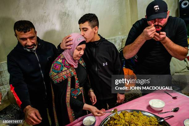 Ahmad Salaima, a 14-year-old Palestinian released under an extended truce deal, kisses his mother as food is served to celebrate his return at...