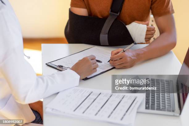 doctor and patient sit and talk. filling medical insurance form - work injury stock pictures, royalty-free photos & images