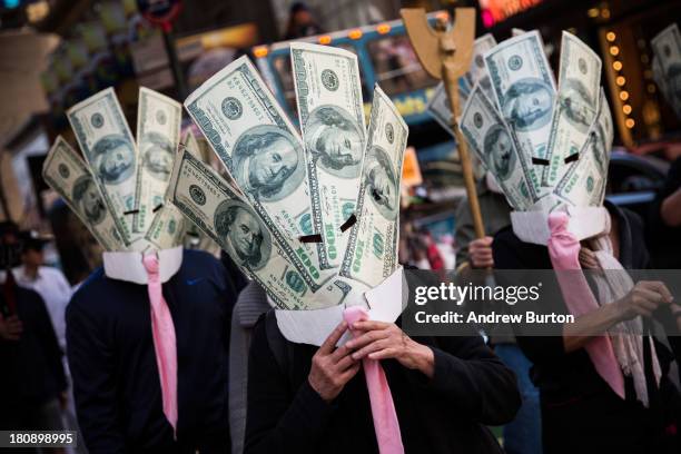 Occupy Wall Street protesters wearing masks made out of enlarged dollar bills act in a short skit in Times Square on September 17, 2013 in New York...