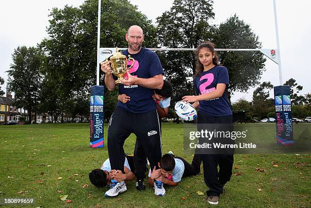 Former England rugby international, Lawrence Dallaglio poses with the Webb Ellis Cup as he is tackled by local children after a coaching session...