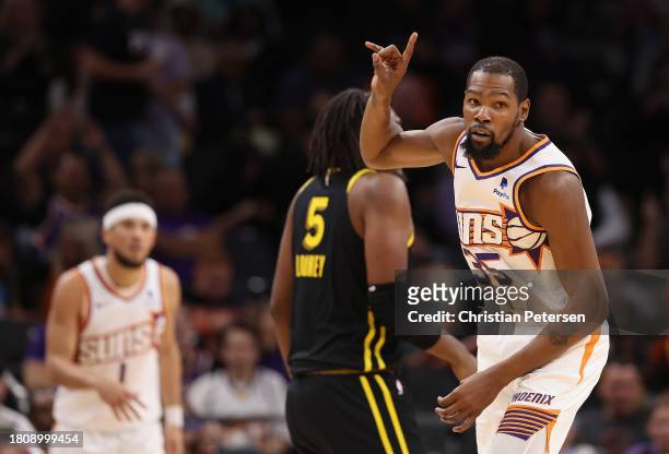 Kevin Durant of the Phoenix Suns reacts to a three-point shot over Kevon Looney of the Golden State Warriors during the second half of the NBA game...