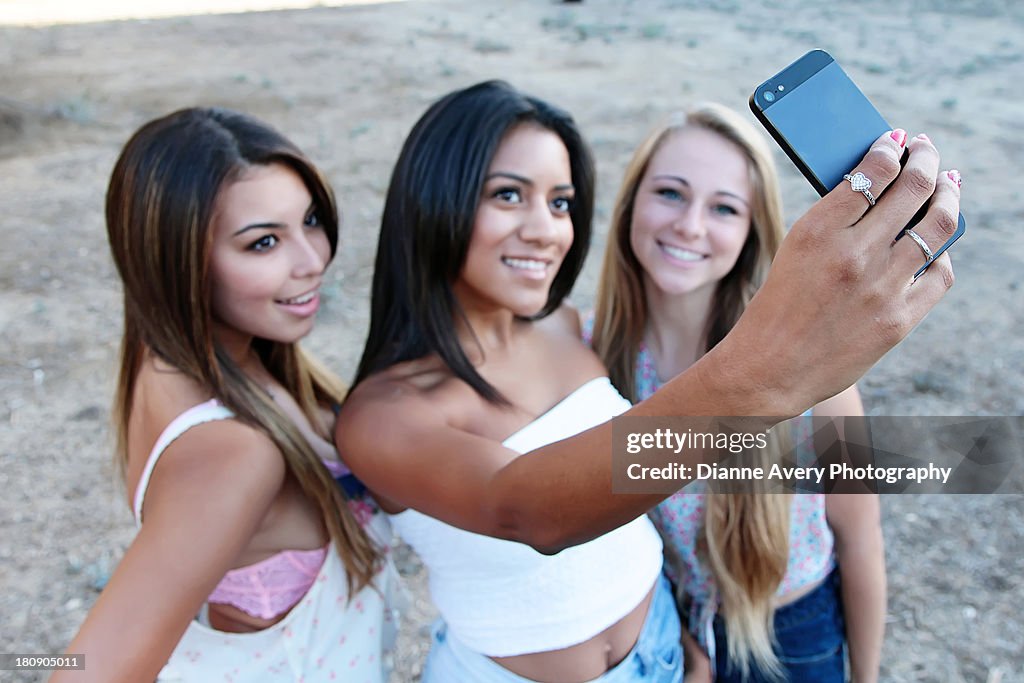 Three teen girls taking selfie with smart phone