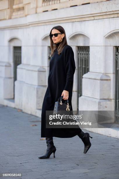 Zina Charkoplia wears black Almada dress, Proenza Schouler boots, Dior bag, YSL sunglasses on November 22, 2023 in Barcelona, Spain.