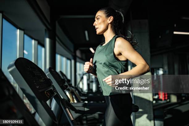 mujer atlética decidida corriendo en cinta de correr en un gimnasio. - centro de bienestar fotografías e imágenes de stock
