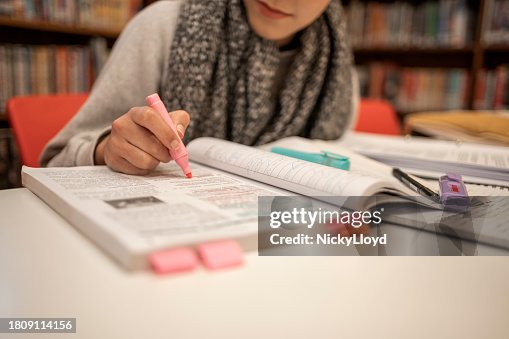 Student highlight notes while studying for exam in library Student highlight notes while studying for exam in library