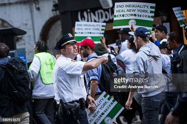 Police officer monitors Occupy Wall Street protesters as they march from the United Nations building to Bryant Park on September 17, 2013 in New York...