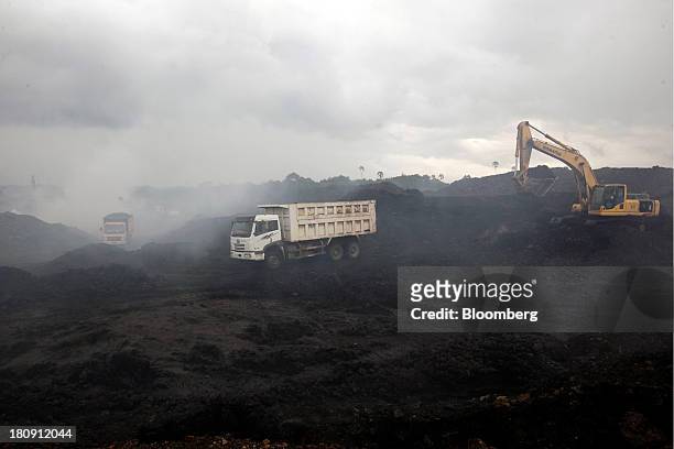 Trucks and excavators operate in the smoke at the PT Exploitasi Energi Indonesia open pit coal mine in Palaran, East Kalimantan province, Indonesia,...