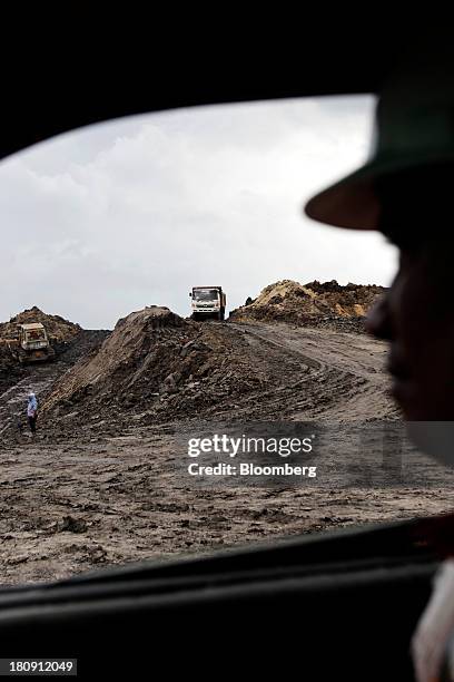 Worker watches trucks and excavators operating at the PT Exploitasi Energi Indonesia open pit coal mine in Palaran, East Kalimantan province,...